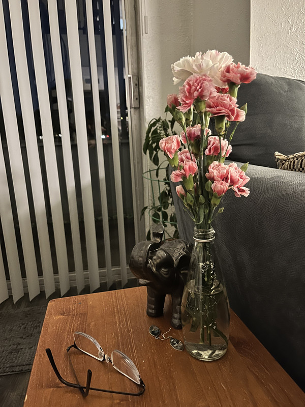 a small pink and white flower arrangement in a glass bottle