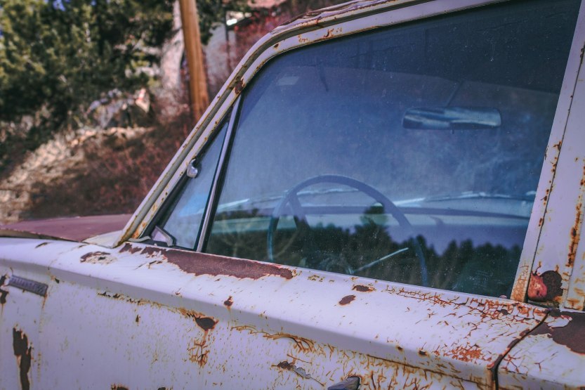 rusty used car with visible corrosion on the door and window frame