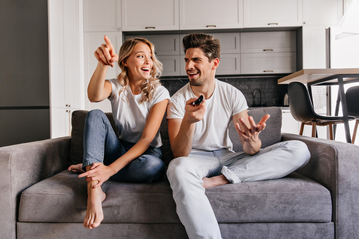 interested-blonde-lady-watch-tv-indoor-portrait-smiling-couple-sitting-cozy-couch.jpg