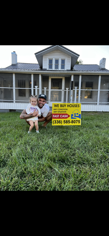 Skylar McGee and daughter at a property with We Buy Houses sign
