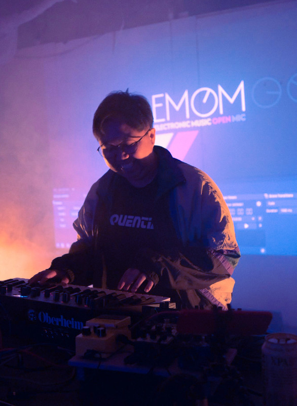 A picture of floatwav, aka Bea, smiling while playing a synthesiser