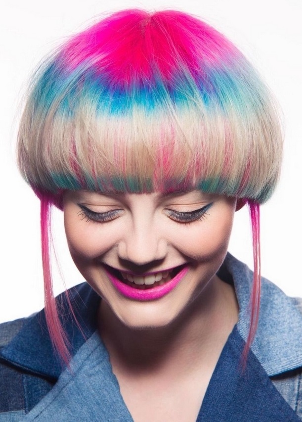 A smiling girl with a short jellyfish haircut on blonde hair tinted with pink and green tones