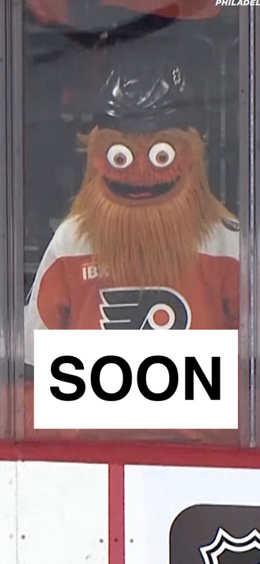 Gritty, unblinking, is holding a sign that says SOON