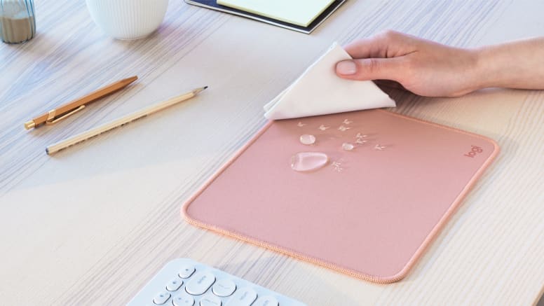 Detalle de una mano limpiando la superficie resistente a derrames del Mouse Pad Logitech Studio Series.