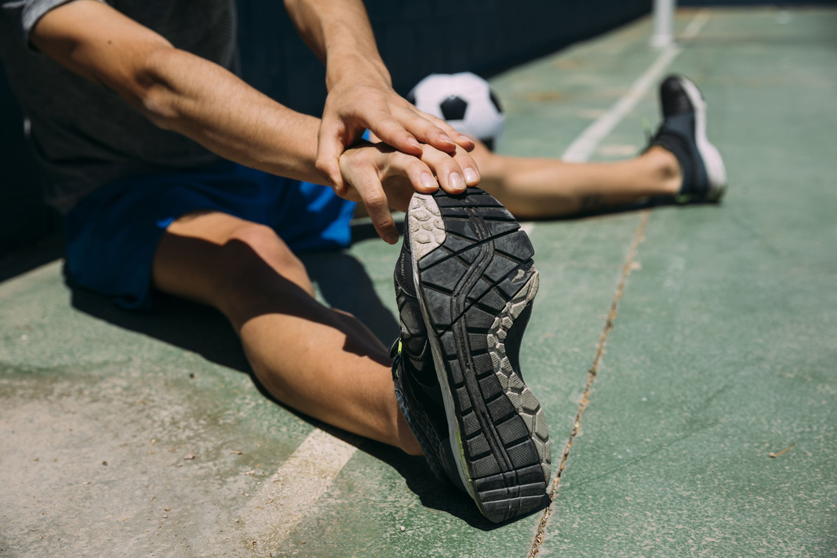 adolescente-esticando-o-pe-no-campo-de-futebol-1.jpg