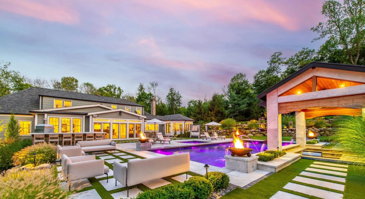 Landscaped outdoor living area with pool, lounge seating, fire features and covered pavilion