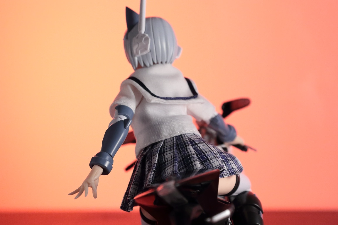 A back view of a 1:12 scale diecast model of the RC8 in white and VFG Kairos girl wearing a 1/12 White Collar Check Sailor Uniform Set in blue