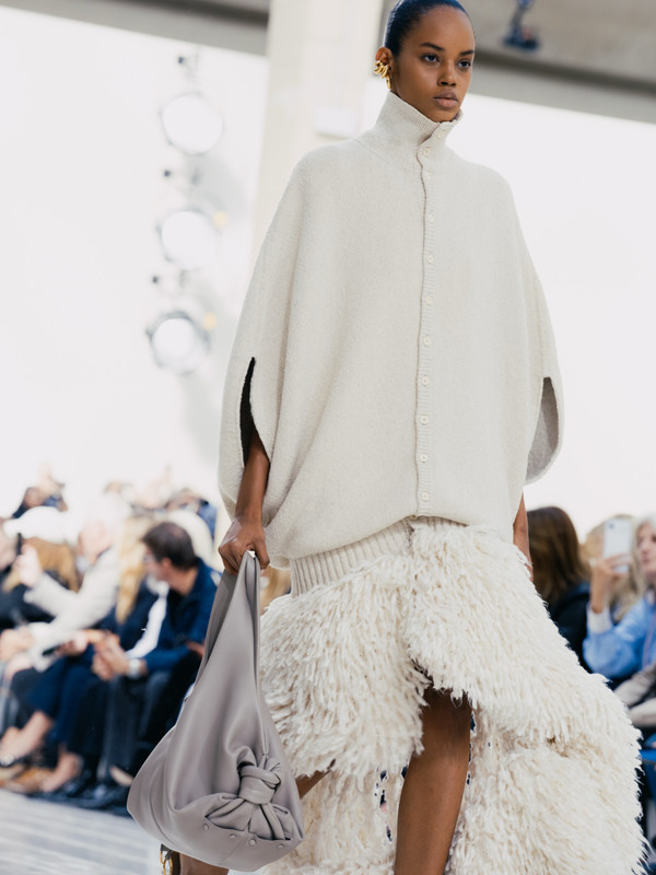 Balenciaga Summer 27, maglia e volumi morbidi Look Balenciaga Summer 27 con maglia bianca oversize, gonna effetto piume e borsa morbida