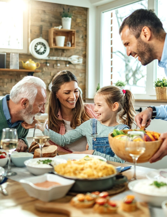 Happy family (grandfather, father, mother, daughter) having lunch