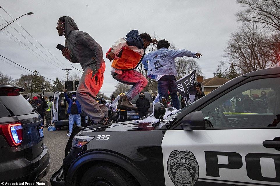41635204-9460619-Men-jump-on-the-hood-of-a-police-car-after-a-family-said-a-man-w-a-332-161822587865