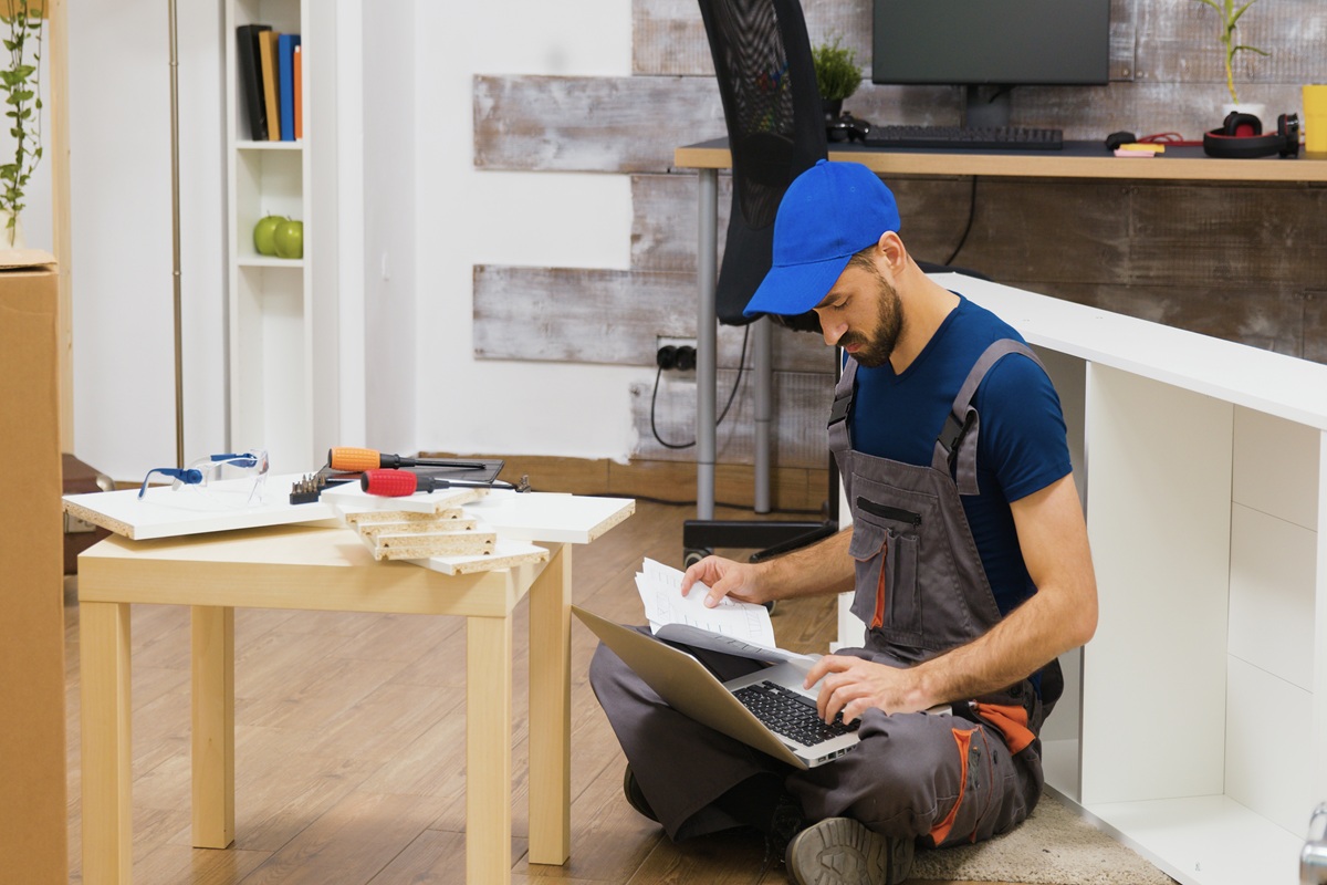 furniture assembly worker uses laptop consult instructions handyman doing good job