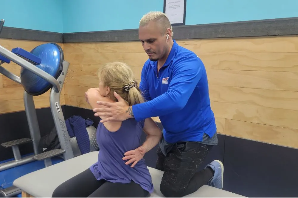 A Sportset coach guiding a client through an assisted stretch