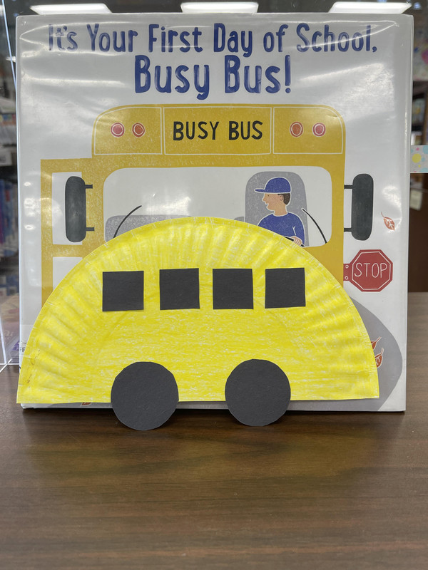 paper plate school bus craft in front of a picture book