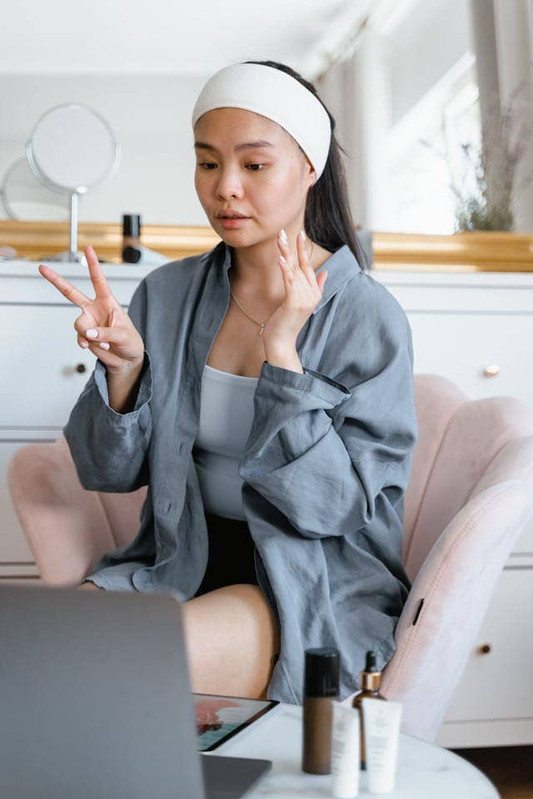 a younge woman doing skincare by following an online influencer's tutorial instead of her's skin needs 