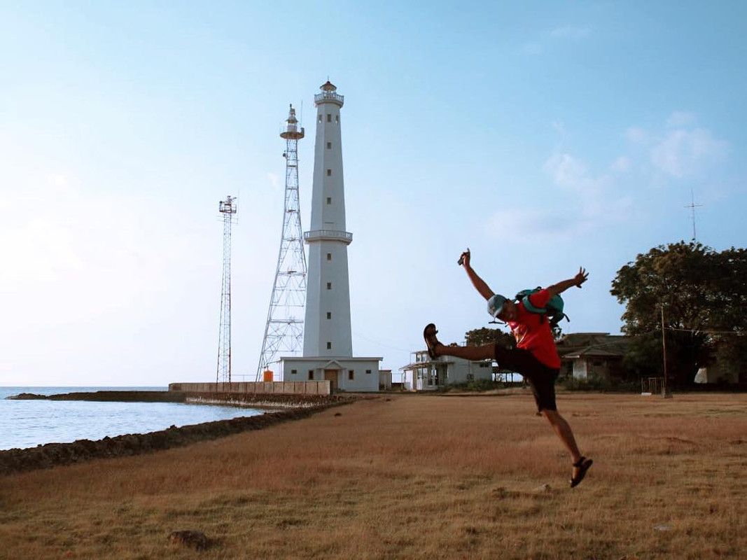 Seorang pengunjung tengah berfoto dengan latarbelakang mercusuar di Pulau Karang Jamuang