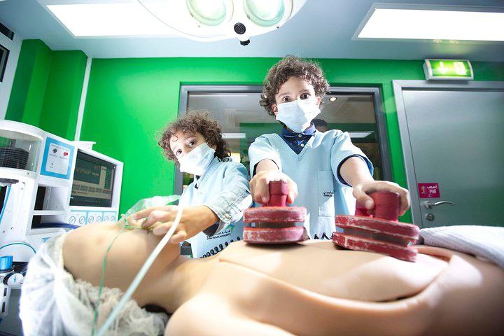 Children dressed as doctors treating a human model inside Kidzania Dubai