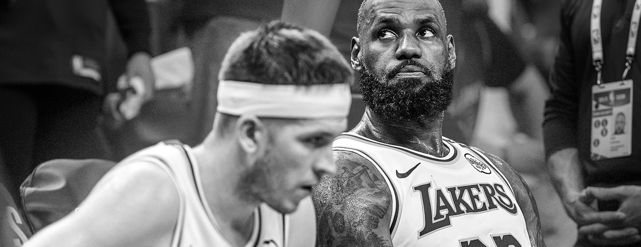 LeBron James no banco de reservas com uniforme do Los Angeles Lakers, olhando para o lado durante uma pausa no jogo.