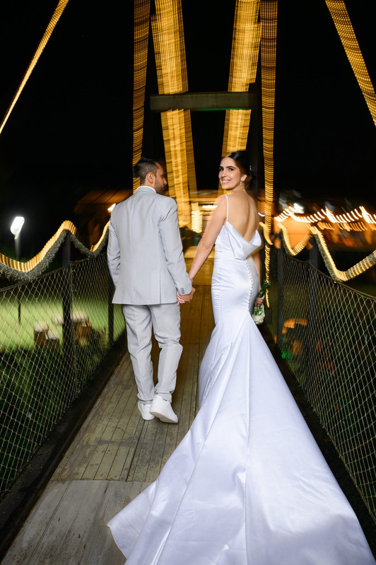Noivos em retrato noturno com vestido longo e arquitetura iluminada