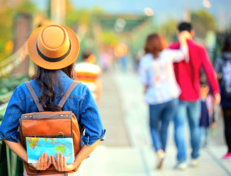 girl holding a map from behind, symbolizing solo travel
