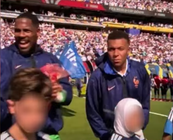 Une enfant voilée accompagne des joueurs avant un match de football