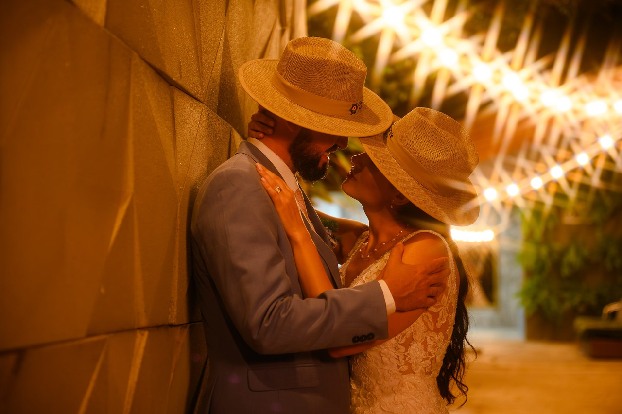 Casal de noivos em retrato noturno com chapéus e luz quente