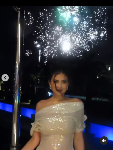 Pose Kylie Jenner dengan latar belakang kembang api.