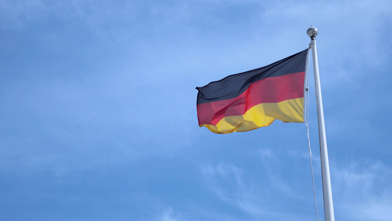 german national flag waving white pole against blue sky