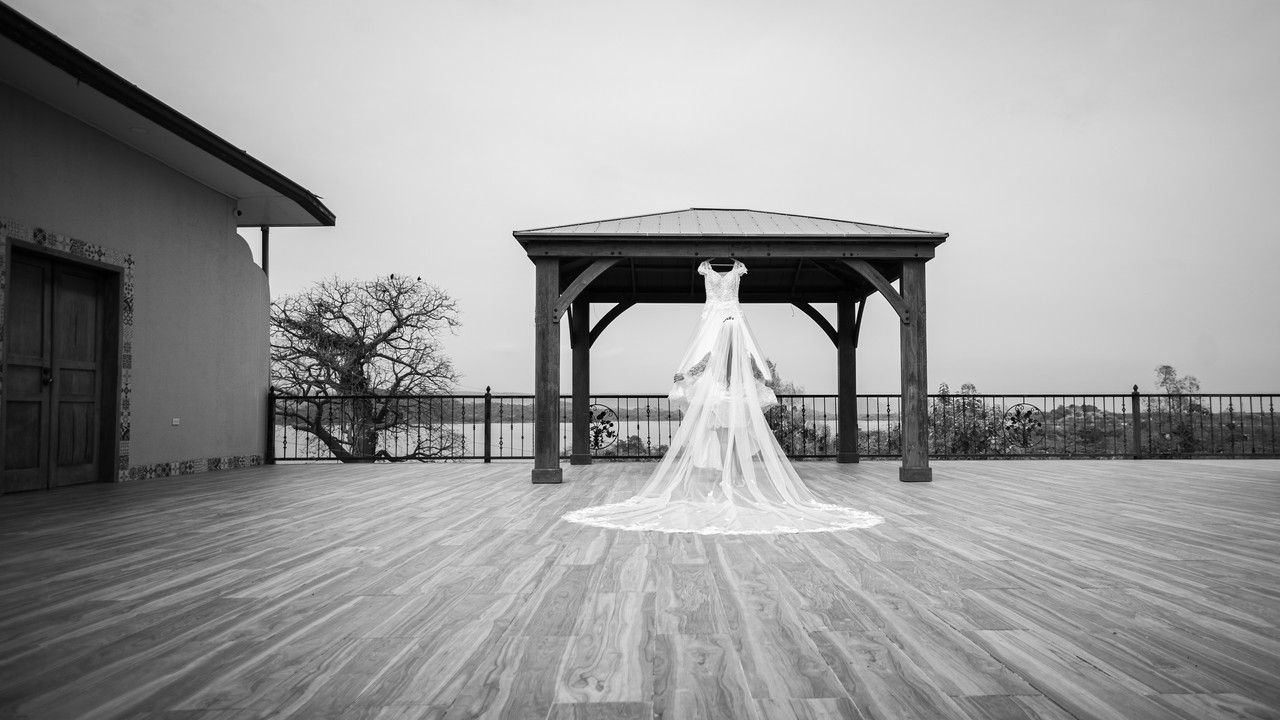 Vestido colgado en espacio abierto, la novia lo abre y ve a lo lejos
