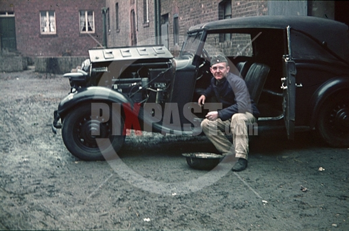 Wehrmacht soldier repairing car in Niederaußem, 