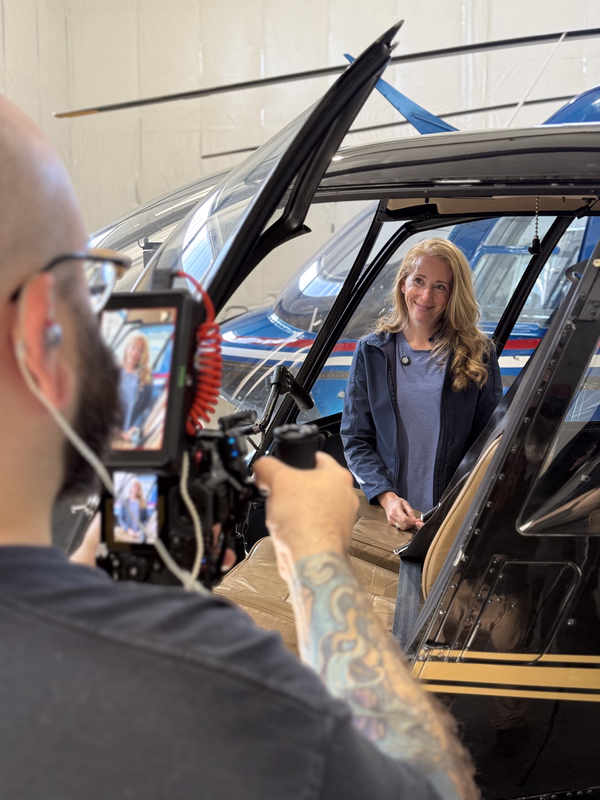 A smiling client being filmed beside a helicopter during a VIVO content shoot