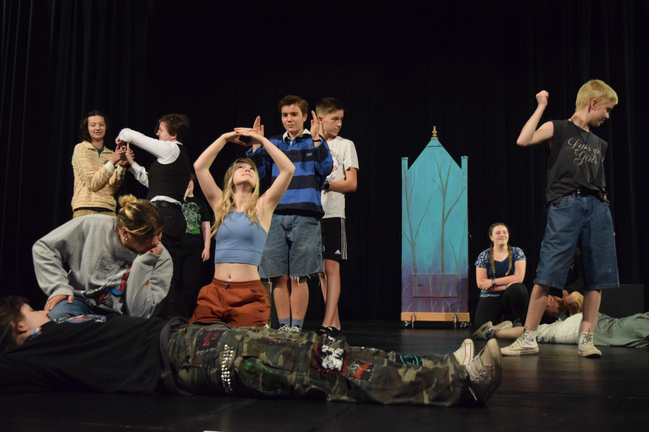 A group of youth engage in an improv game on a stage