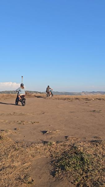 Dos ciclistas en e-bike sobre una explanada frente al mar