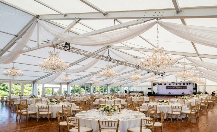 Wedding marquee interior during a ceremony with guests seated and elegant drapery