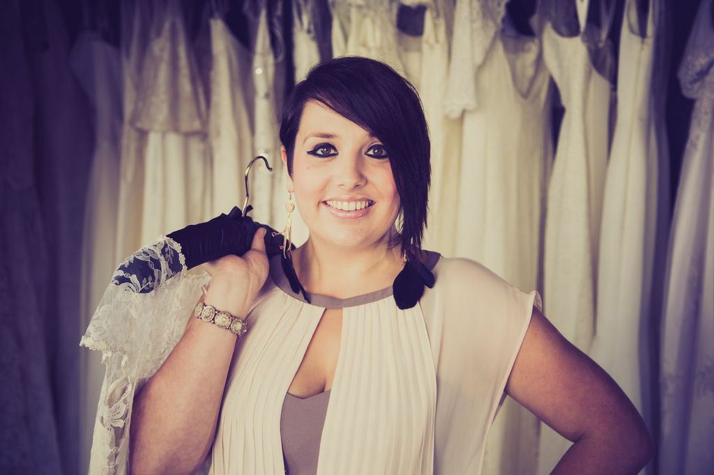 Portrait of Rachel Burgess holding a vintage dress in the shop.