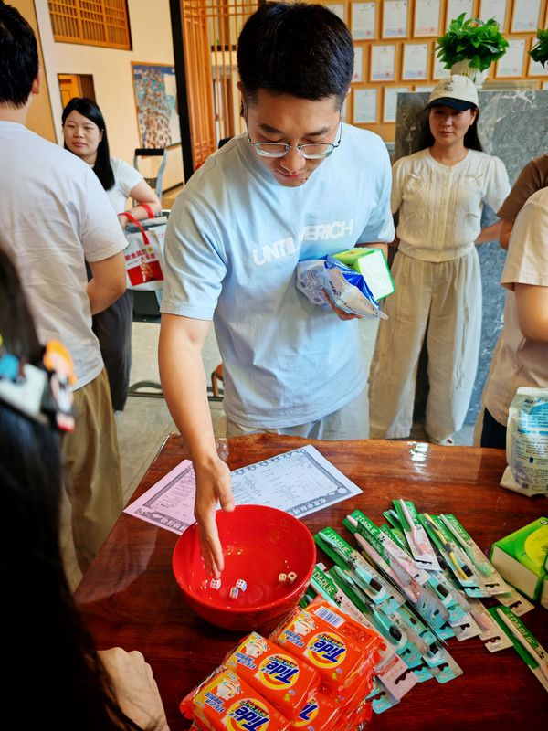 A Heat Press Leader colleague rolling six dice into a red bowl during the traditional Bo Bing game