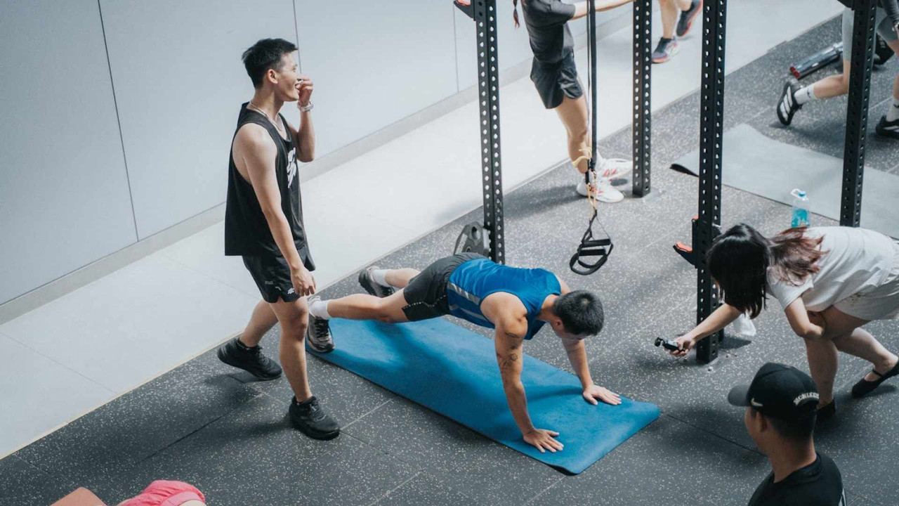 Huấn luyện viên quan sát học viên tập plank kết hợp mountain climber tại Active Fox
