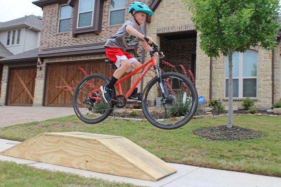 a boy is jumping on a bike ramp.