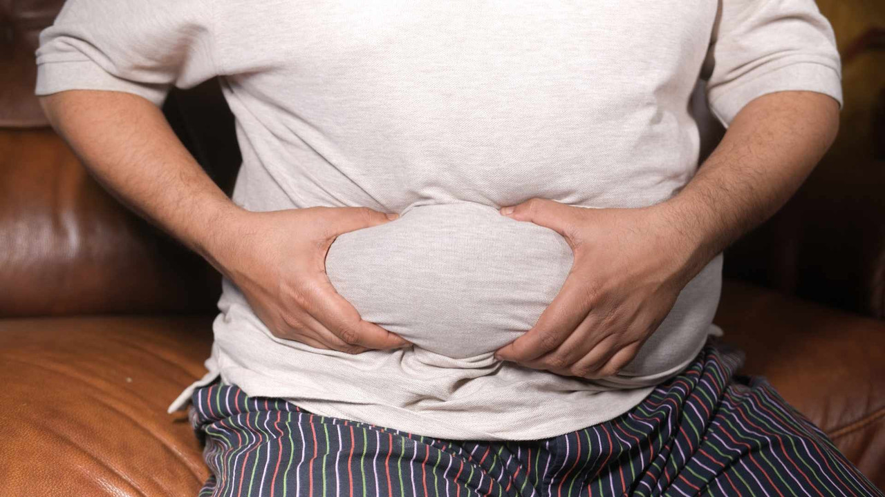 Nam giới ngồi ôm vùng bụng tích mỡ, minh họa 3 nguyên nhân gây mỡ nội tạng ở dân văn phòng ít vận động