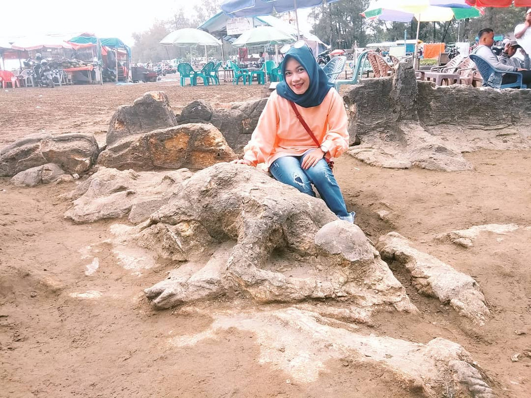Pengunjung sedang memegang batu Malin Kundang di Pantai Air Manis