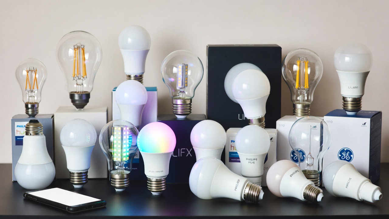 Collection of smart light bulbs from various brands arranged on a table with smartphone control