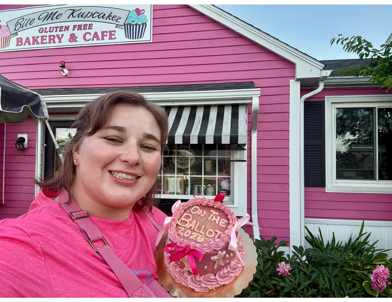 Rebecca Boutin outside Bite Me Kupcakez with confetti and an 'On the Ballot 2026' cake