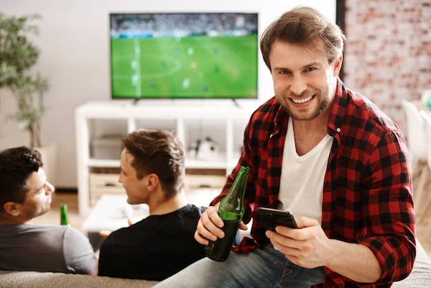 Бесплатное фото Футбольные фанаты с мобильным телефоном и пивом