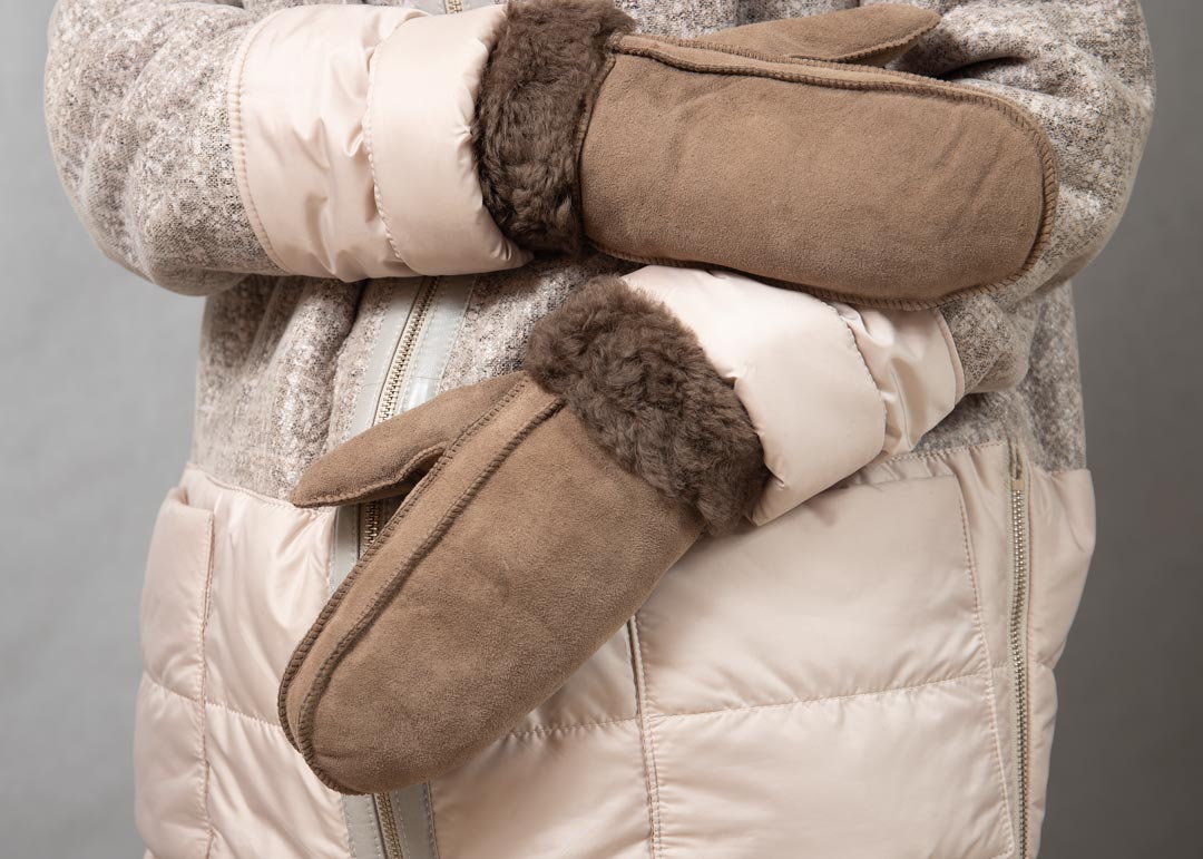 Женщина проверяет качество меха в варежках в магазине