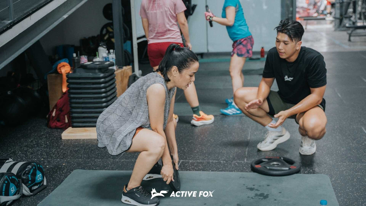 HLV Fox Strength của Active Fox chỉnh form squat 1-1 cho hội viên nữ trong buổi tập tăng cơ giảm mỡ tại phòng gym TP.HCM