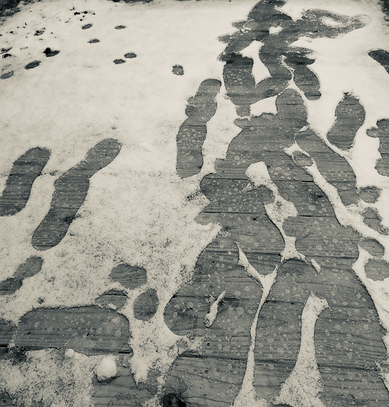 Footprints in melting snow on wooden deck