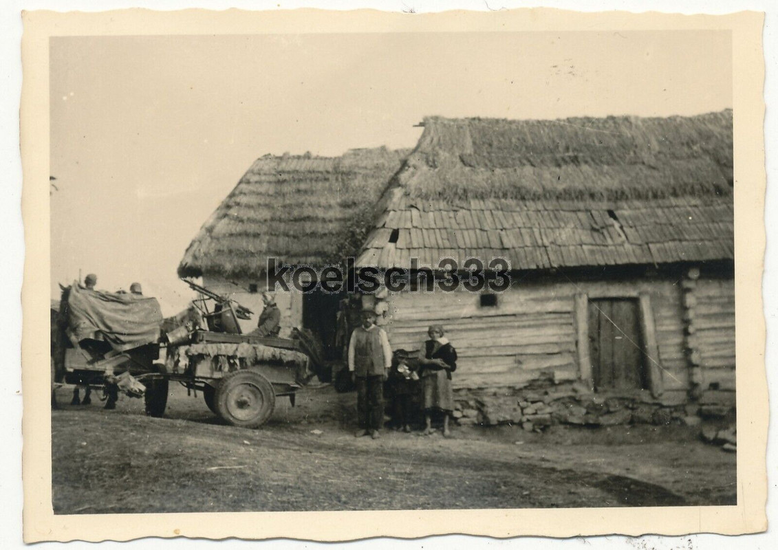 Foto Landser im Flak MG Zwillingssockel Anhänger an einem Bauernhaus im Osten