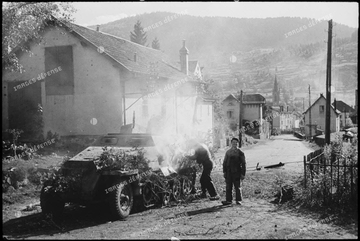 Une automitrailleuse semi-chenillée allemande Sd.Kfz 251 vient de sauter sur une mine dans le villag