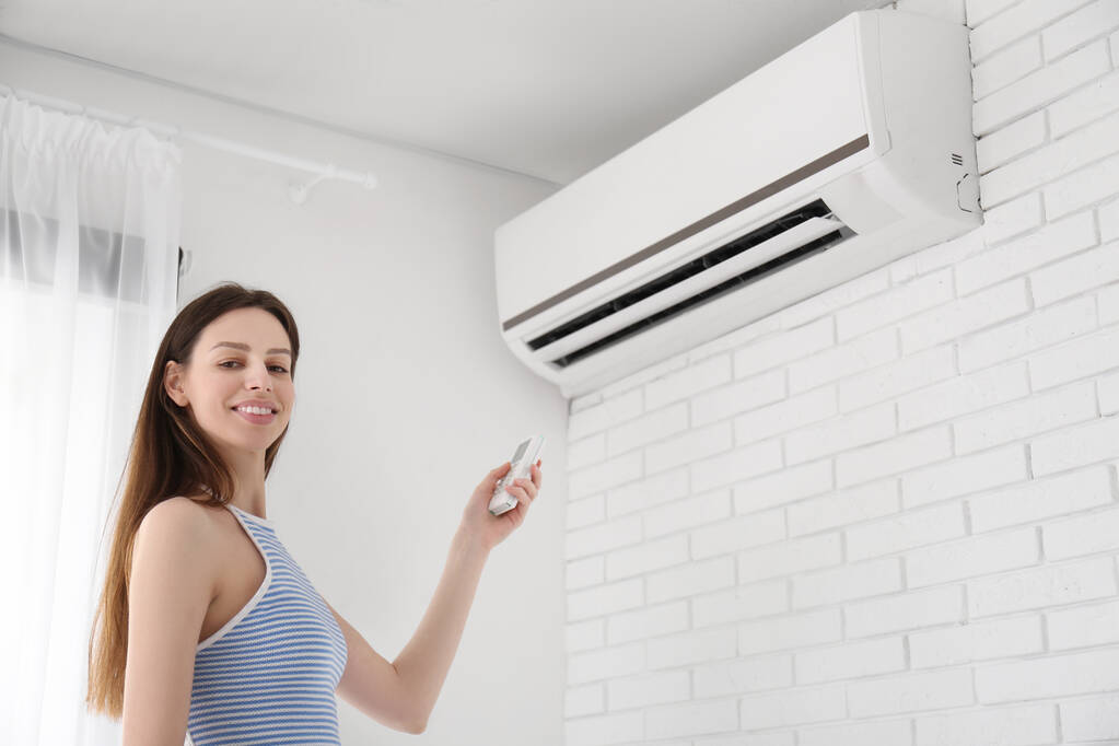 Woman adjusting air conditioner temperature