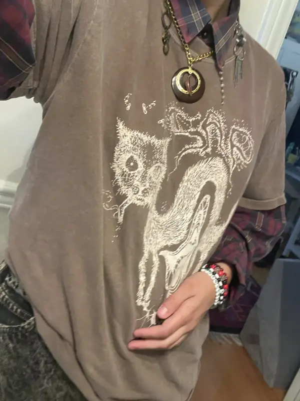 a torso selfie of myself in a brown sap (band) t-shirt with a flannel underneath, a chunky necklace, acid-washed jeans, and some kandi bracelets.