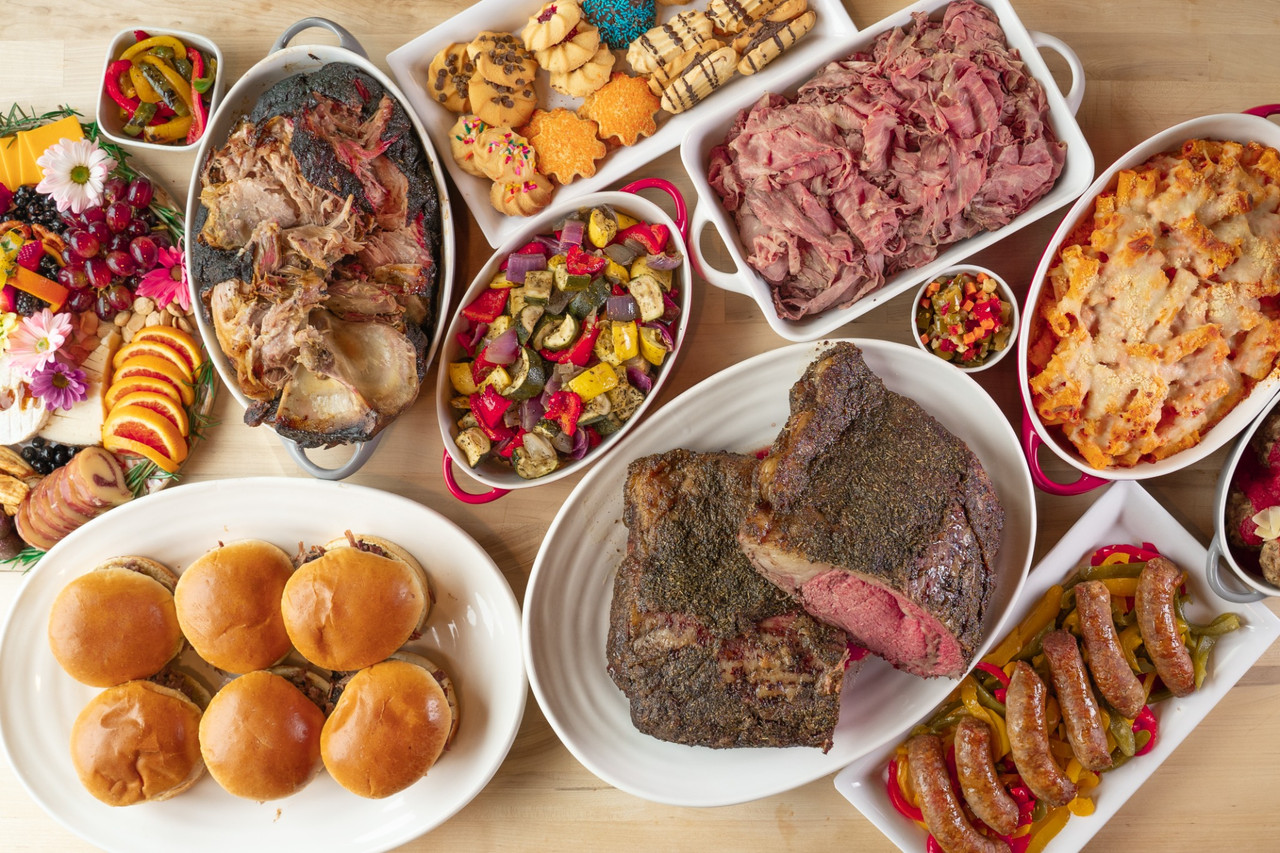 Catering buffet spread with carved beef, sliders, pasta, vegetables, sausage, charcuterie, and desserts photographed in Chicago